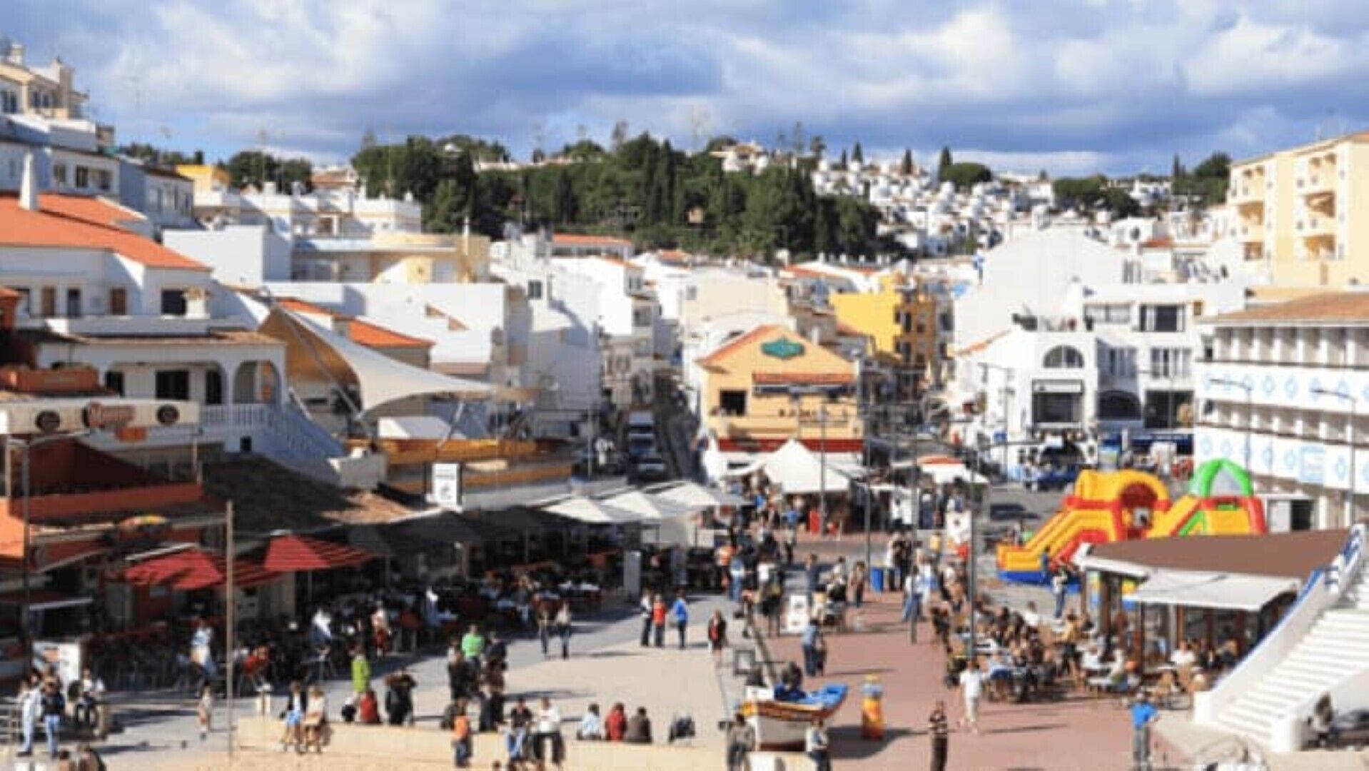 A bustling square with buildings, a playground, and people.