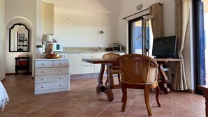 A spacious living area with a dining table, chairs, a TV, and a kitchen area. - Traditional Portuguese house with lot of privacy and space. (Carvoeiro lagoa)