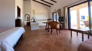 A bedroom with a bed, a desk, and a chair. There is a window with curtains and a view of the outside. - Traditional Portuguese house with lot of privacy and space. (Carvoeiro lagoa)
