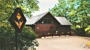 A rustic log cabin with a metal roof, surrounded by trees and a gravel driveway. - Beautiful Views of The Great Smoky Mountains From Anywhere Indoors or Out! (Bryson City)