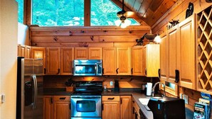A kitchen with wooden cabinets, a stainless steel refrigerator, a microwave, and a stove. - Beautiful Views of The Great Smoky Mountains From Anywhere Indoors or Out! (Bryson City)