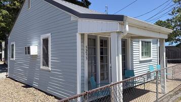 A small, single-story house with a porch, a number '5235' on the door, and a chain-link fence in front.