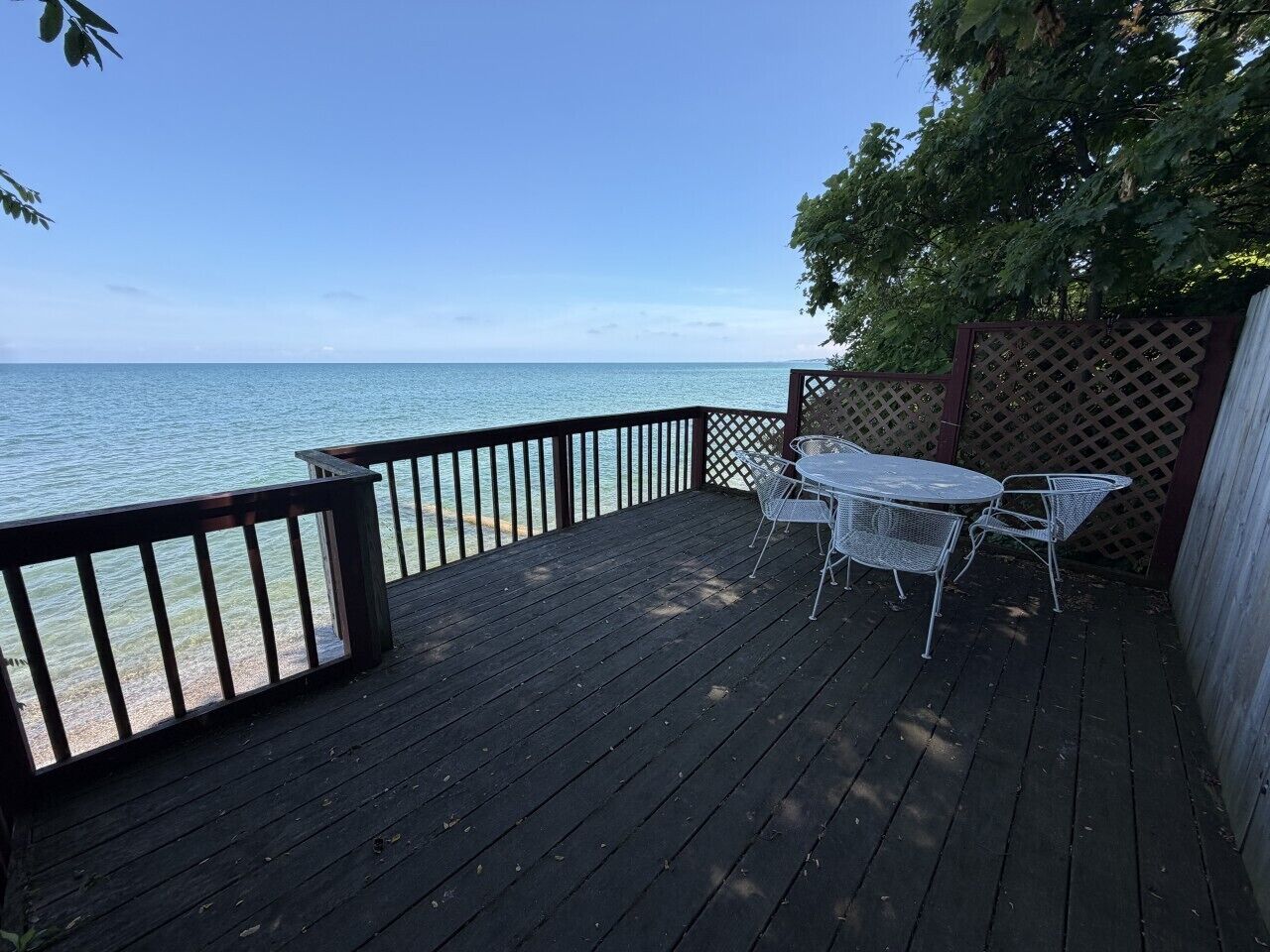 A wooden deck with a table and chairs, overlooking a body of water.