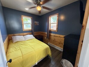 A bedroom with a bed, a ceiling fan, two windows, and a dresser. - 3 Cottages on Strip, Lakefront, AC, Fire pit, (Geneva)