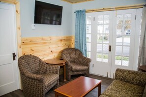 Ein Zimmer mit zwei gemusterten Sesseln, einem kleinen Holztisch und einem Sofa.