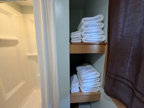 Un bagno con doccia, un portasciugamani con asciugamani piegati e una tenda da doccia.