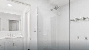 Une salle de bain moderne avec un meuble-lavabo blanc, un miroir et un espace douche.