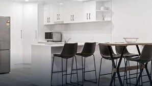 Une cuisine moderne avec des meubles blancs, un four à micro-ondes et un coin repas équipé de quatre chaises.