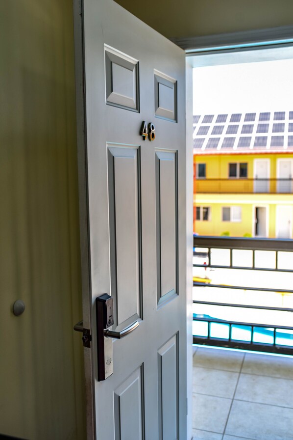 Una puerta blanca con teclado numérico, un ventanal pequeño y un picaporte de metal.
