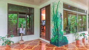 A room with large windows, a tiled floor, and potted plants.