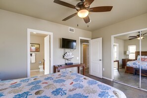 Une chambre à coucher avec un lit, un ventilateur de plafond, une télévision et un bureau.