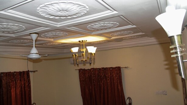 Una habitación con techo decorado, candelabro y ventilador.