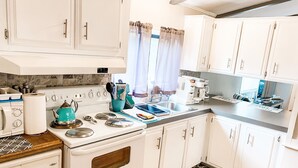 A modern kitchen with white cabinets, a stove, a sink, and a coffee maker. - Tacoma Hidden Gem 1Bed/1bath w/ Kitchen and Laundry (Tacoma)
