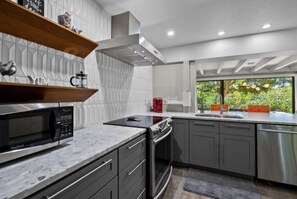 Enjoy cooking in this well-equipped kitchen with a stainless steel microwave, oven, and range hood.