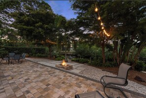 An outdoor patio with a fire pit, seating area, and string lights. - Canal-front, Gulf Access Sanctuary kayak and bicycle to the beach (Naples)