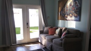 Ein Wohnzimmer mit einer Couch, einem Streifenmuster-Teppich und einem Bild an der Wand.