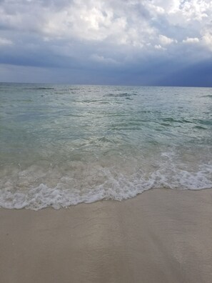 A beach with clear water and waves gently touching the shore.