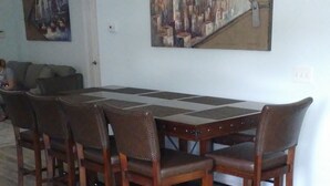 Ein Essbereich mit einem langen Holztisch, sechs Stühlen, einem Bild an der Wand und einer Chandelier.