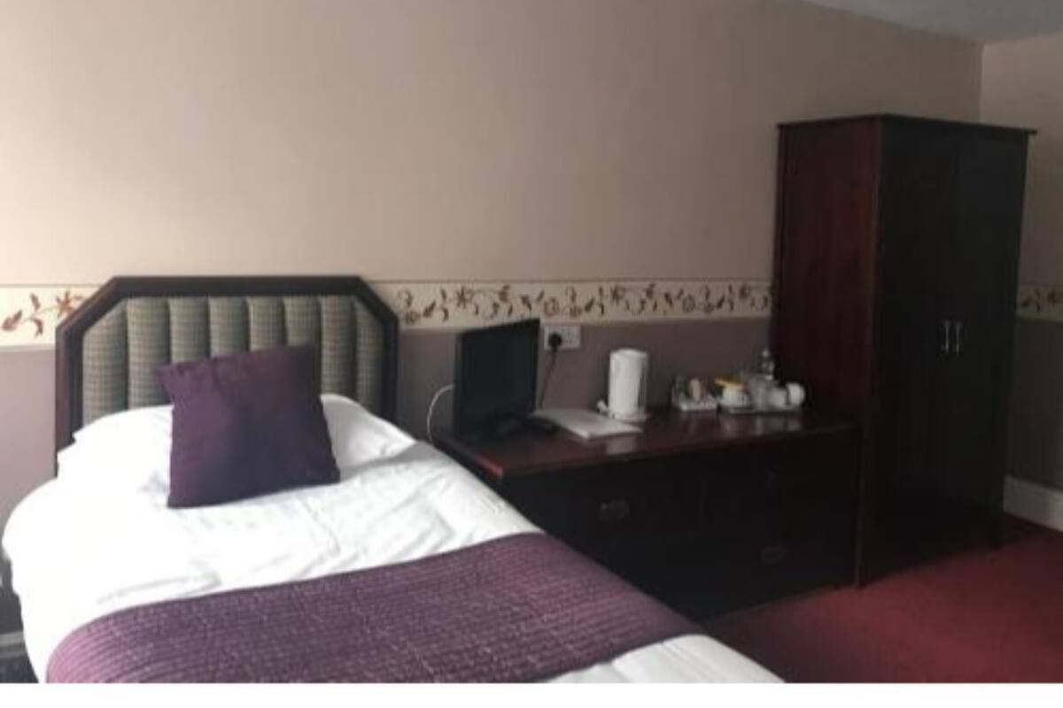A hotel room with a bed, a desk, a computer, and a wardrobe.