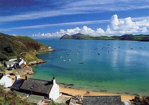 Un pueblo costero con casas a lo largo de la orilla, un mar tranquilo y un cielo despejado.