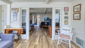Un salon spacieux doté d’un parquet, d’un bureau en bois, d’un fauteuil à bascule blanc et d’un canapé.