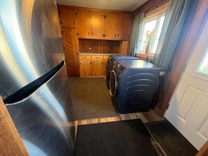 Compact kitchen with washing machine and stainless steel refrigerator.