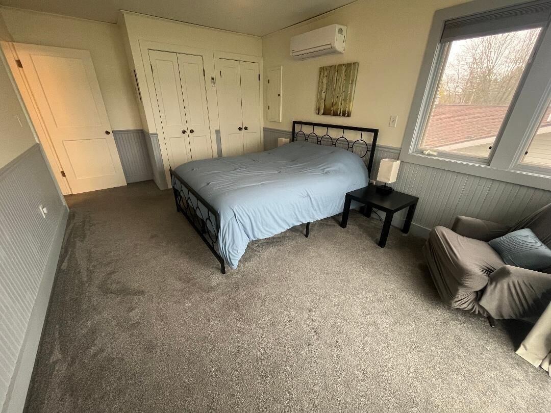 Une chambre à coucher avec un lit, une table de chevet, une fenêtre et une porte.