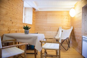 Une cabane en bois avec une table et des chaises, une plante en pot et une fenêtre.