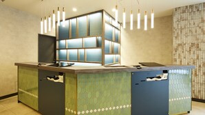 Un comptoir d’accueil au design moderne, agrémenté d’un motif géométrique et d’un grand panneau lumineux.