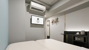 Une chambre d’hôtel dotée d’un grand lit, d’une télévision à écran plat, d’un minibar et d’un climatiseur fixé au mur.