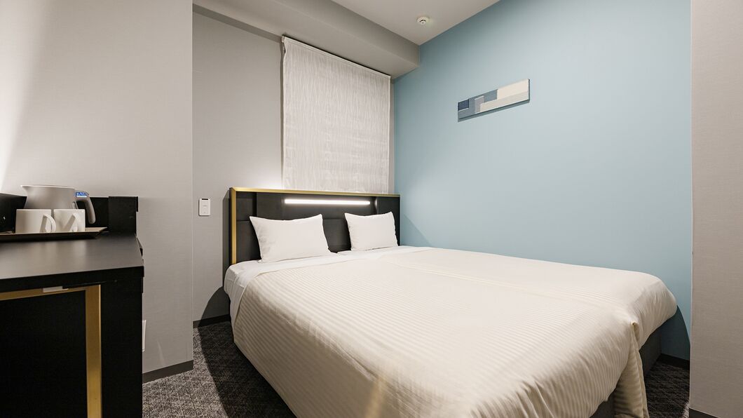 Une chambre d’hôtel avec un lit, une table de chevet et une fenêtre avec un rideau.