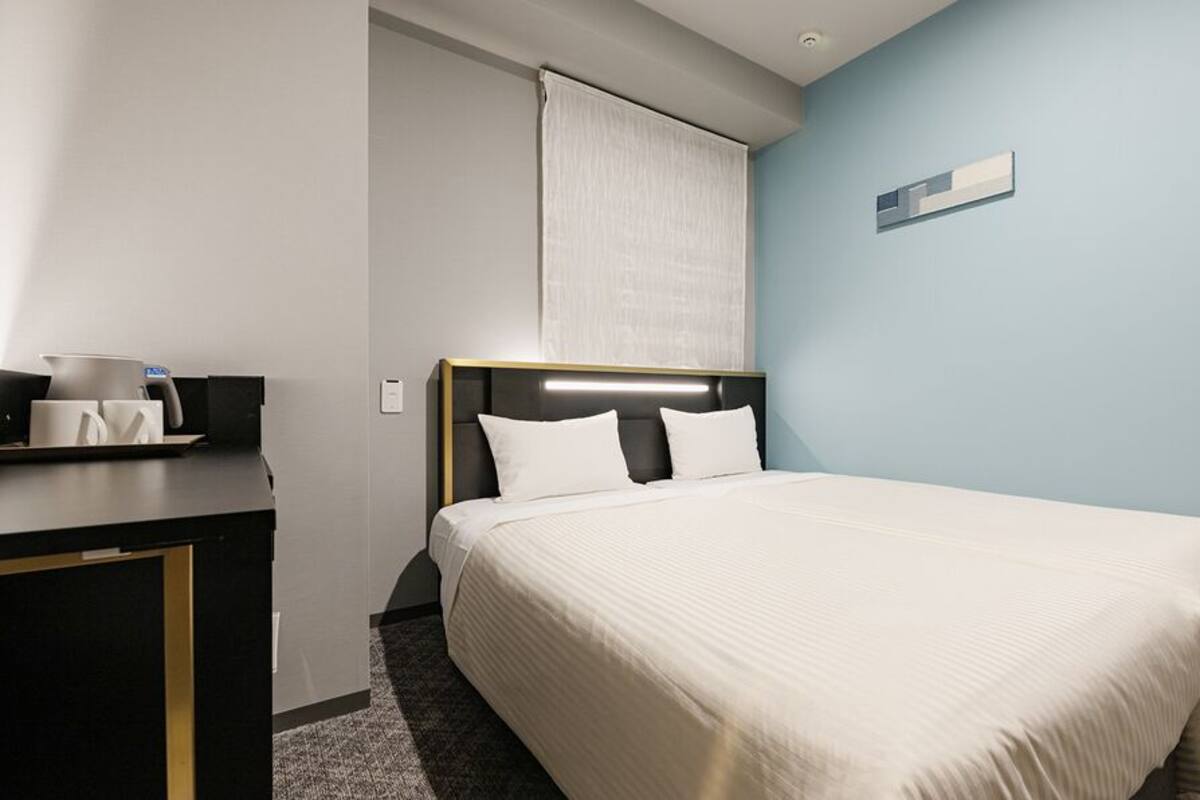 Une chambre d’hôtel avec un lit, une table de chevet et une fenêtre avec un rideau.