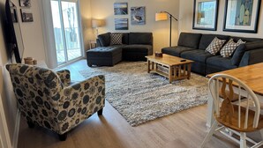 A living room with a sectional sofa, a loveseat, a coffee table, and a dining table with chairs. - Spacious clean condo,  large pool, plus many extras.   Perfect for families. (Oak Island)