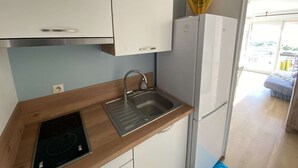 Een compacte keuken met een ingebouwd spoelgedeelte, een fornuis en een witte koelkast.