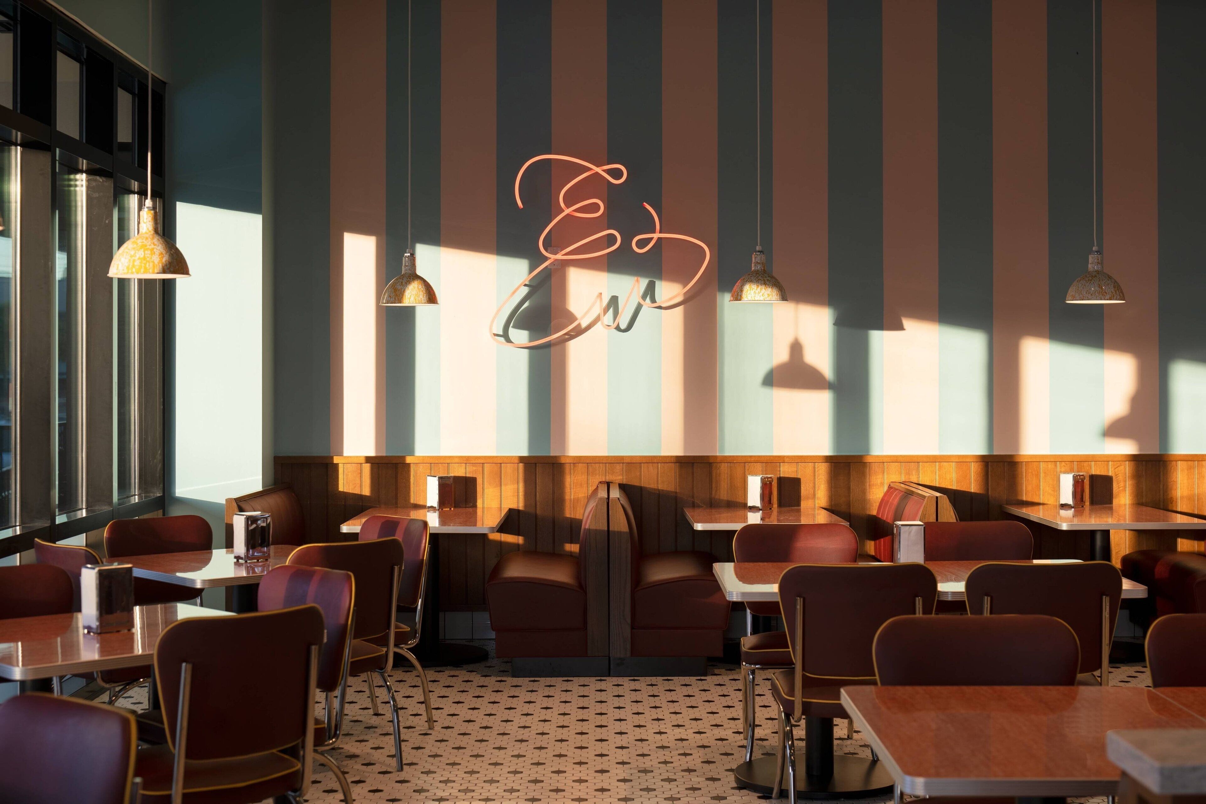 A restaurant with striped walls, booths, and pendant lighting.
