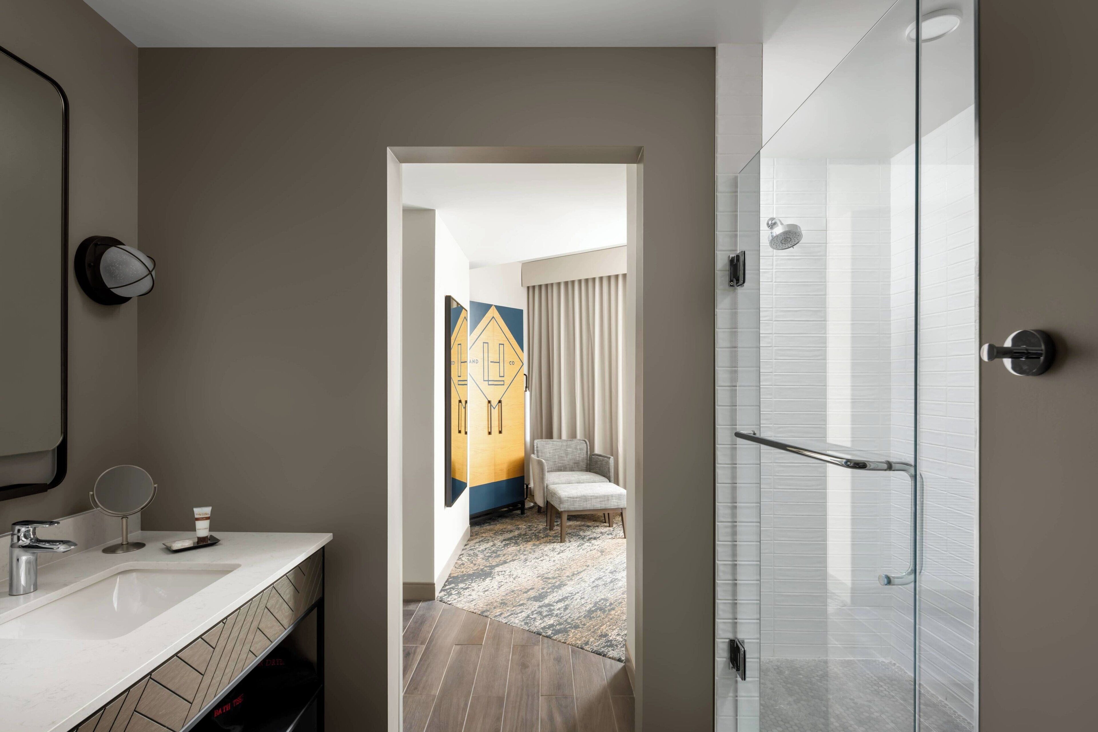 A modern bathroom with a white sink, mirror, and glass shower enclosure.