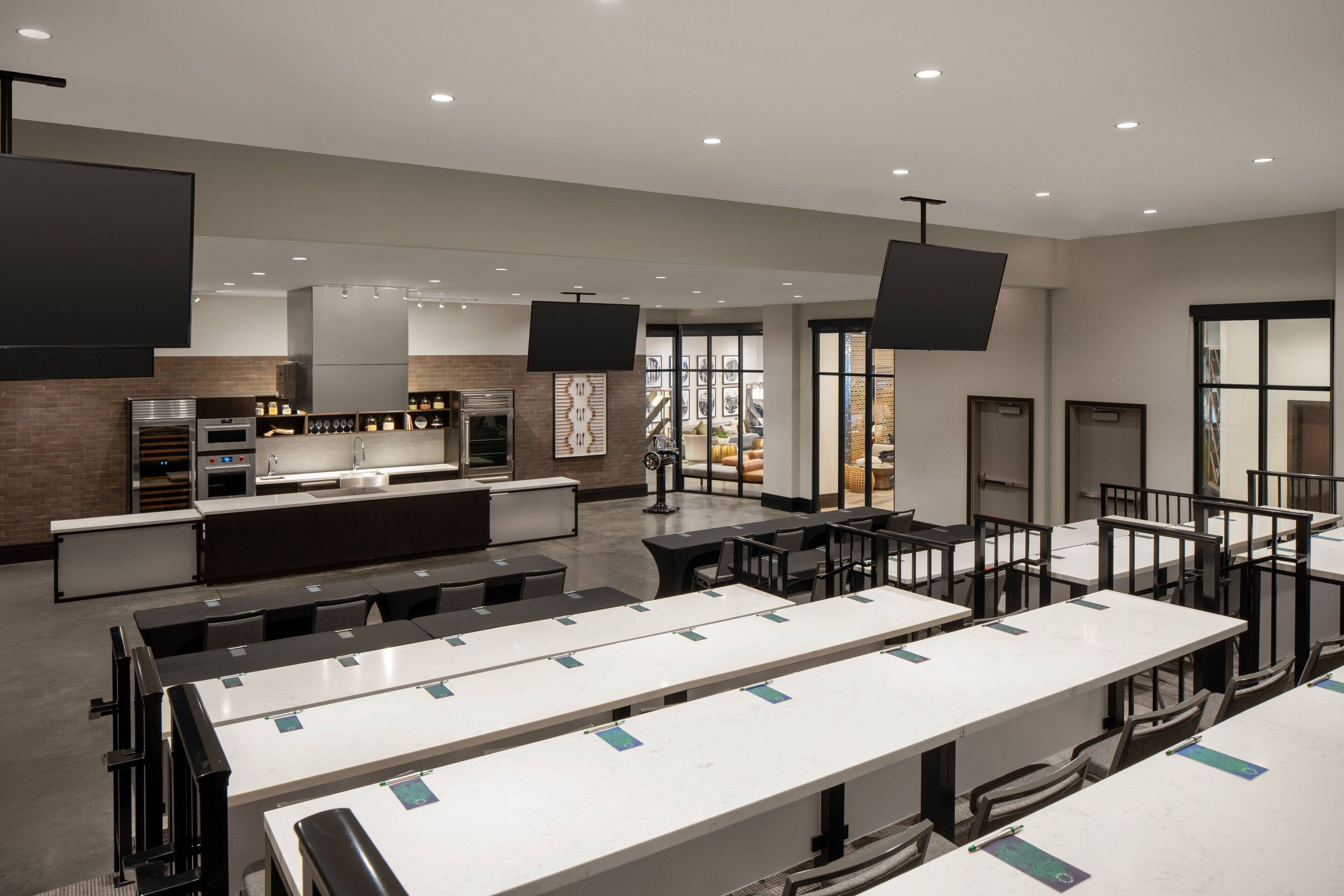 Una cocina moderna con electrodomésticos integrados, un comedor con mesas y sillas, y grandes ventanales con vistas.