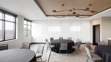Un salón de conferencias con una mesa redonda, sillas y una lámpara de araña moderna.