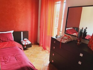 Quarto com cama, cômoda, espelho e janela com cortinas.
