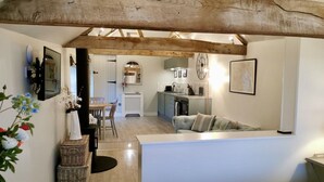 Une pièce chaleureuse avec un plafond en bois, un coin repas avec une table et des chaises, un coin cuisine et un canapé.