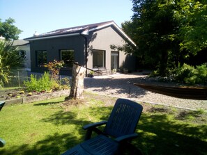 A house with a sloped roof, a front door, and a small porch area. - Exclusive Garden Apartment (Galway)
