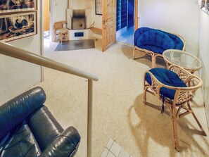 Ein Wohnzimmer mit einem schwarzen Ledersofa, zwei blauen Sesseln, einem Glastisch und einem Kamin.