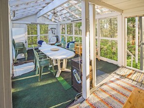 A sunroom with a table and chairs, large windows, and a view of the outdoors.