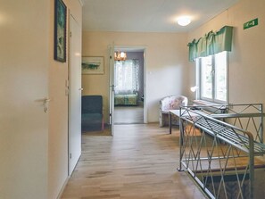 Un corridoio con un letto, una sedia e una finestra con tende.