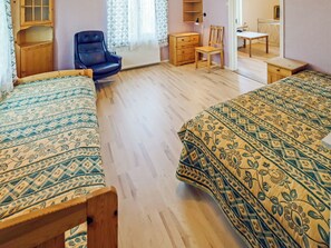 A room with two beds, a chair, a dresser, and a desk.