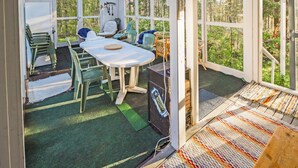 Ein Wintergarten mit Tisch und Stühlen, großen Fenstern und einem Deckenventilator.
