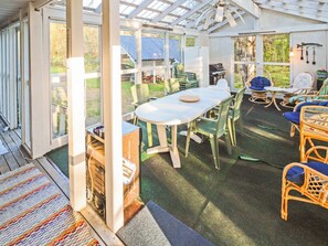 Un patio aménagé, avec une table et des chaises, un barbecue et des meubles en osier.