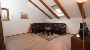 Un espace de vie de style loft avec un canapé en cuir noir, une table basse en bois, une guitare et une lampe.
