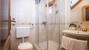 Une salle de bain moderne avec une douche à parois de verre, des toilettes et un lavabo surmonté d’un miroir.
