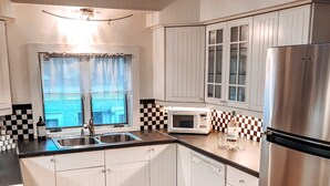 A modern kitchen with white cabinets, a stainless steel refrigerator, a microwave, and a wooden floor. - Spacious home in the Heart of Downtown Newport! Walk Everywhere  (Newport)